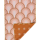 This picture shows an 18"X30" oversized towel with a corner folded up to show the double sided designs.  The Front design is a rainbow with different orange and pink hues.  The folded part shows a matching orange designs with beige polka dots.  You can also see the waffle weave texture in the picture.