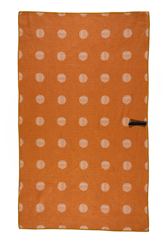 This picture is showing one side of the double sided waffle weave design.  This side features an orange hue with beige polka dots.  It also shows a hook that you can use to hang the towel to dry.
